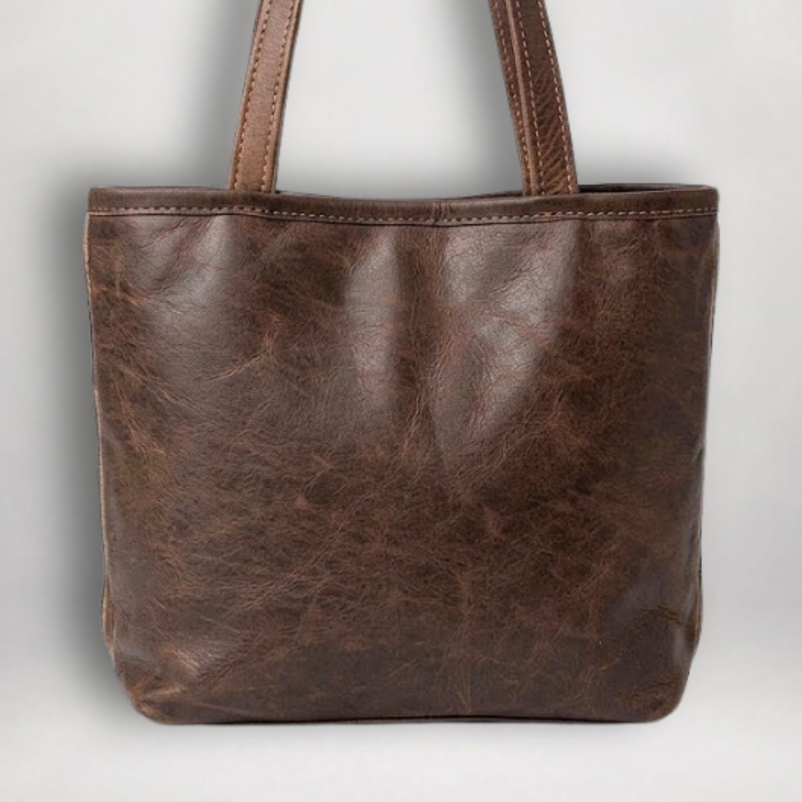 Back view of handcrafted leather tote featuring a full-grain leather panel and matching leather shoulder straps.